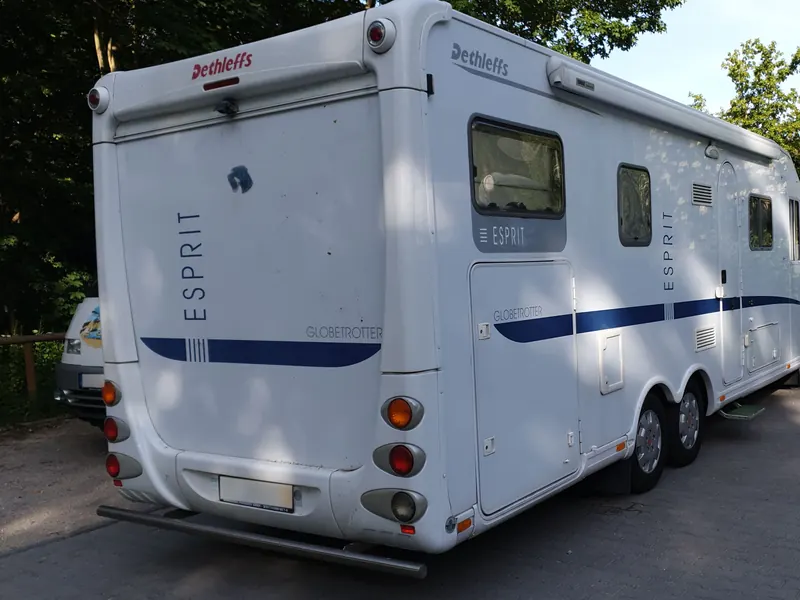 Weißes Wohnmobil mit blauem Werksdekor vor der Folierung, Ansicht von hinten