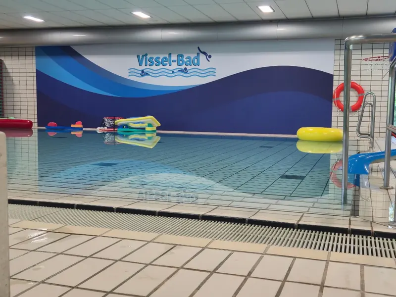 Großformatiges Wandbild mit Wellenmotiv und Schriftzug in einem Hallenbad