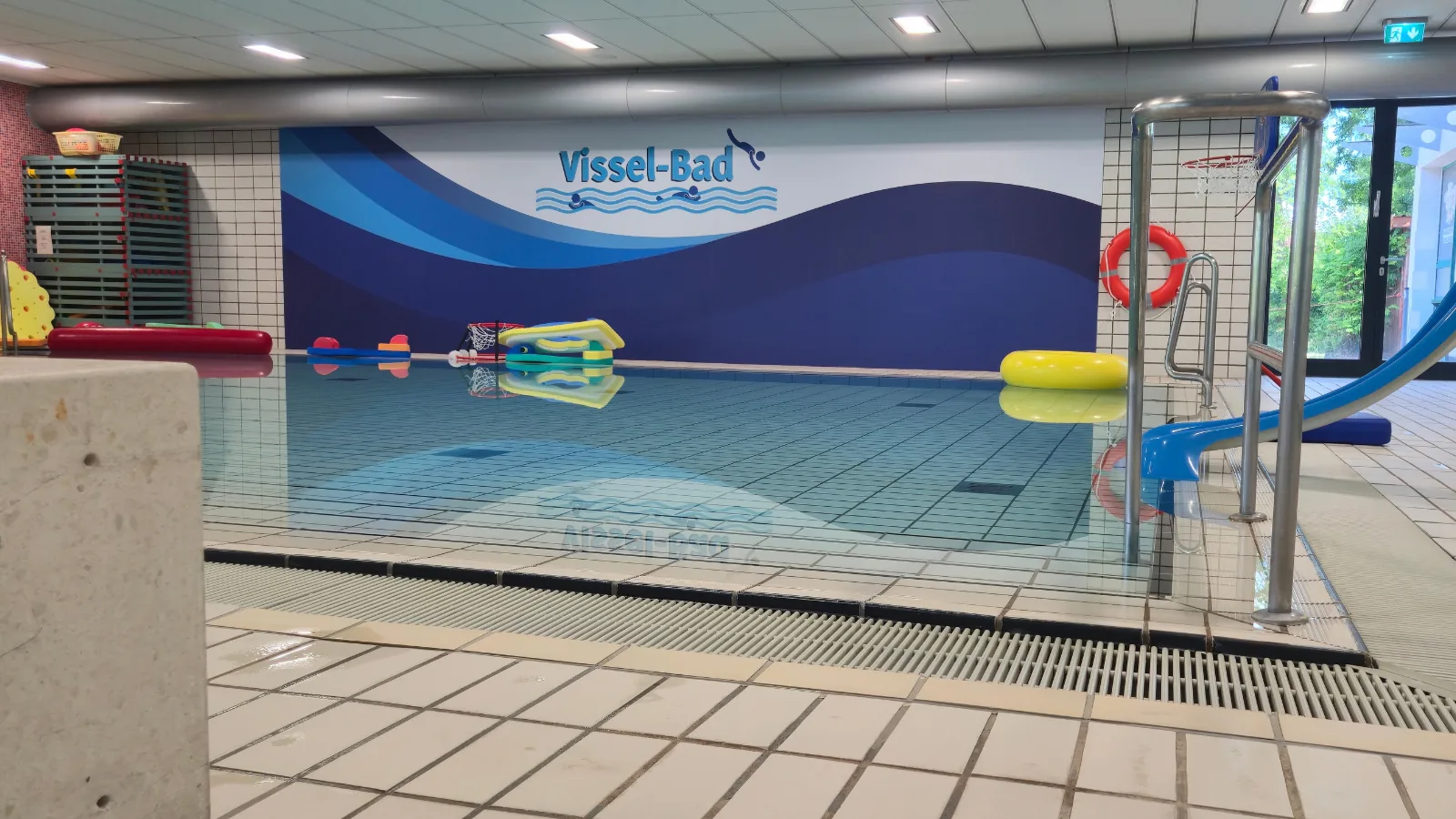 Großformatiges Wandbild mit Wellenmotiv und Schriftzug in einem Hallenbad