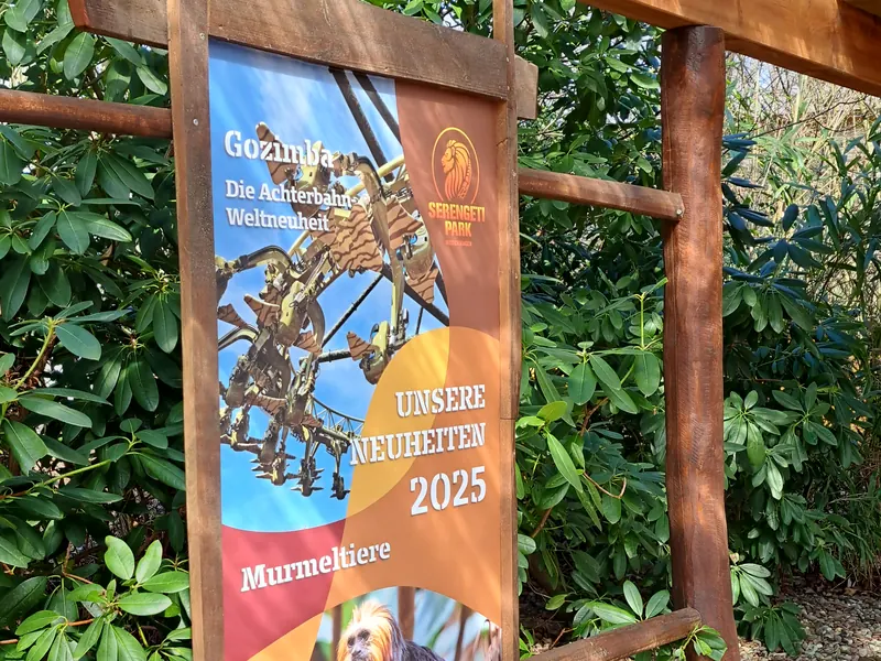 Bedrucktes Banner im Holzrahmen in einem Freizeitpark mit den Neuheiten der Saison