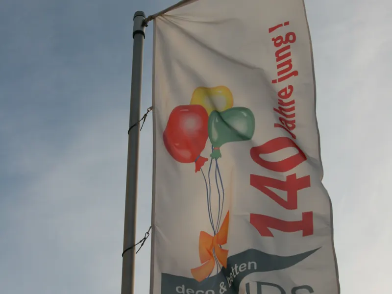 Bedruckte Fahne mit Jubiläumsmotiv am Fahnenmast