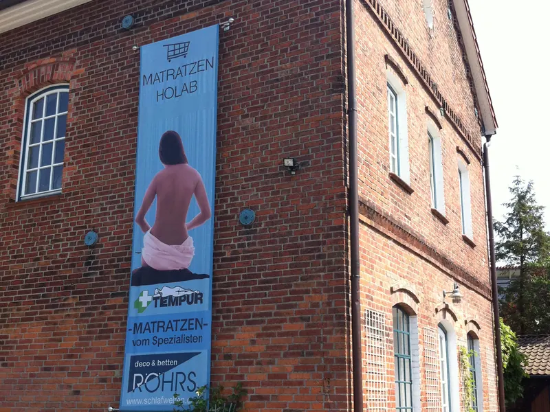 Hochformatiges Werbebanner an einer Klinkerfassade