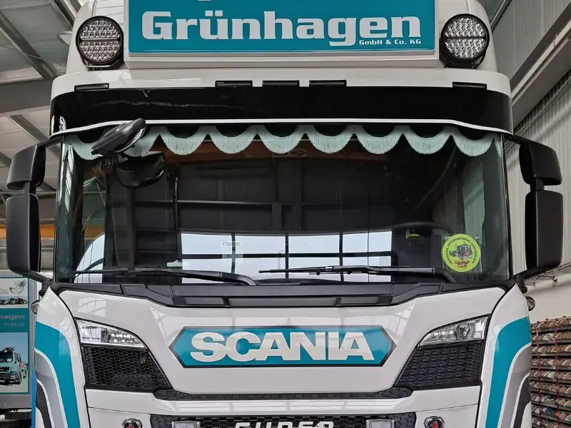Front einer weißen Sattelzugmaschine mit beschriftetem Dachschild