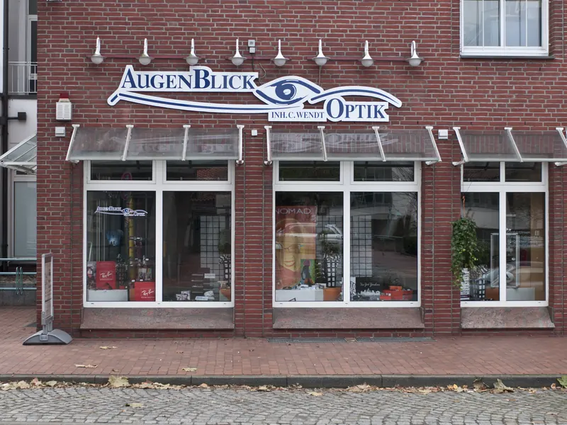 Ladenfront eines Optikers mit großem, ausgeschnittenem Fassadenschriftzug samt Augen-Logo