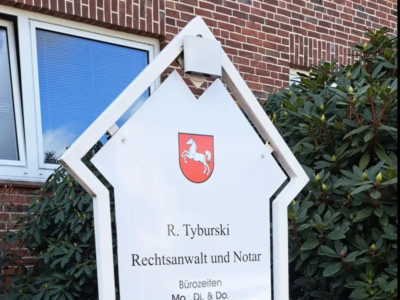 Formschild einer Kanzlei mit Öffnungszeiten vor einem Bürogebäude