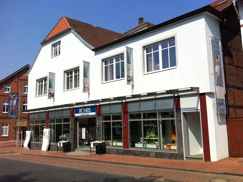 Geschäftshaus mit Fassadenbannern, Eingangsschild und beschrifteten Schaufenstern