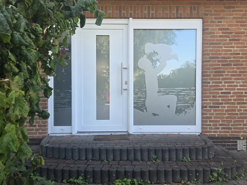 Hauseingang mit Milchglasfolie und ausgeschnittenem Motiv auf dem Seitenfenster