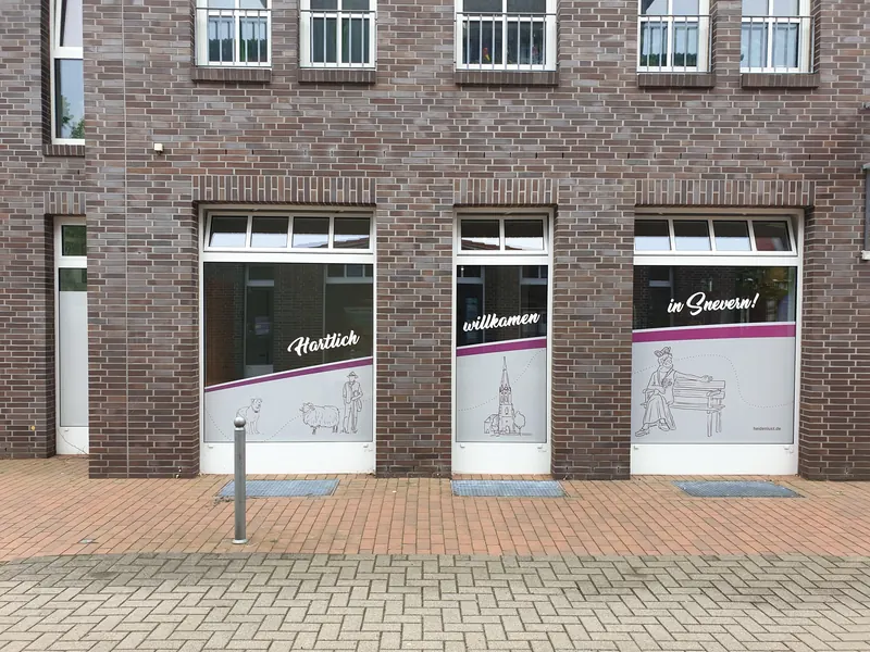 Drei Schaufenster mit Sichtschutzfolie, Zeichnungen und plattdeutschem Willkommensgruß