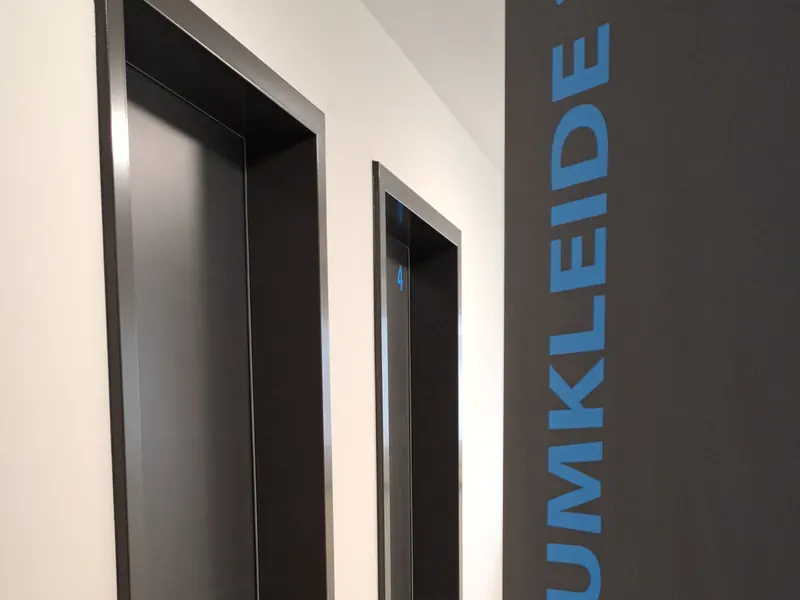 Dunkle Tür mit senkrechtem Schriftzug Umkleide 3+4 in Blau