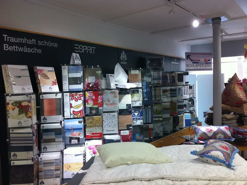 Wandbeschriftung in einem Bettenfachgeschäft mit Schriftzug und Markenlogos über der Warenwand