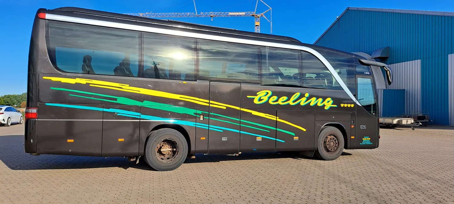 Derselbe Reisebus nach der Vollfolierung in Schwarzmetallic mit farbigem Streifendesign